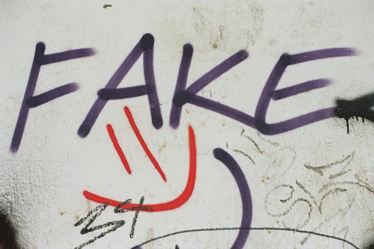 Graffiti featuring the word "FAKE" with a smiley face drawn in red.