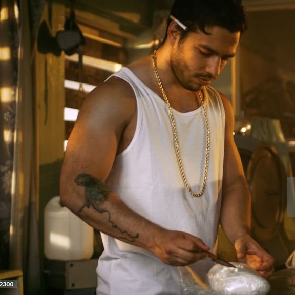 PITC Module 1 Man in a tank top mixing a substance in a bowl, ambient lighting and a relaxed atmosphere.