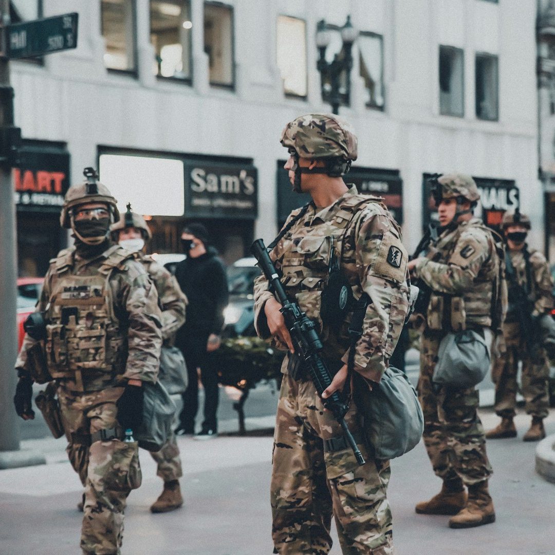 Field Operations Soldiers in military uniforms with rifles walking in an urban area.