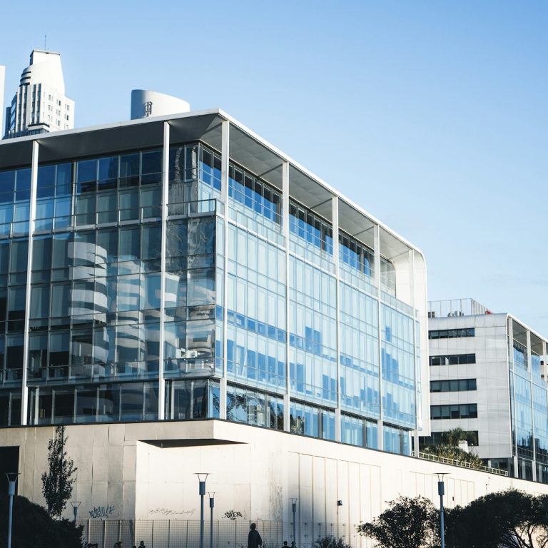 Modern glass office building with a clear blue sky in the background.