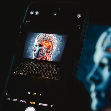 A smartphone displays a digital rendering of a brain next to a keyboard.