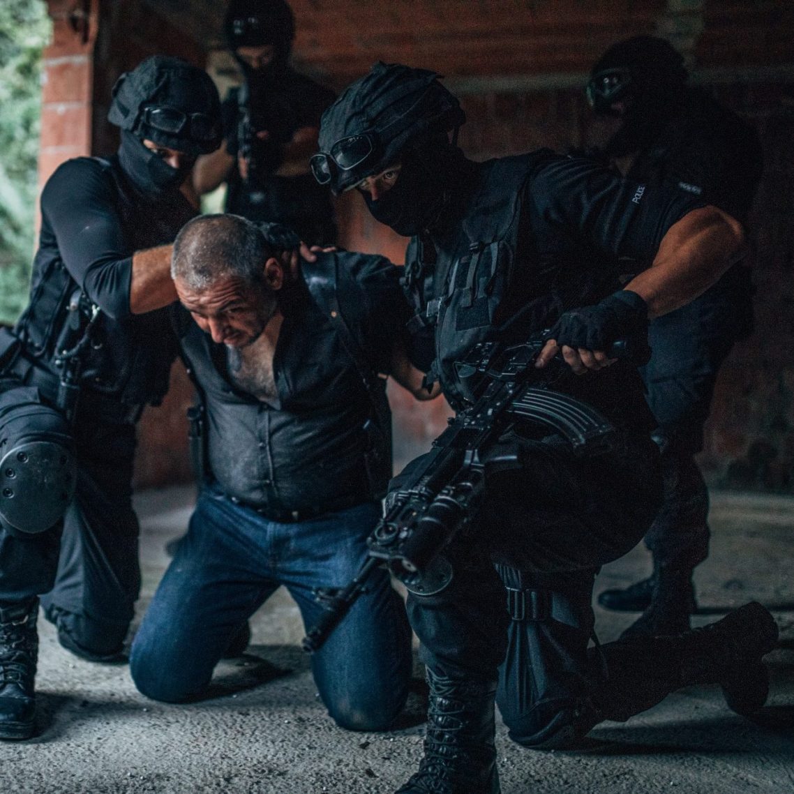 PITC Module 6 Armed tactical officers apprehending a man in a dimly lit, industrial setting.